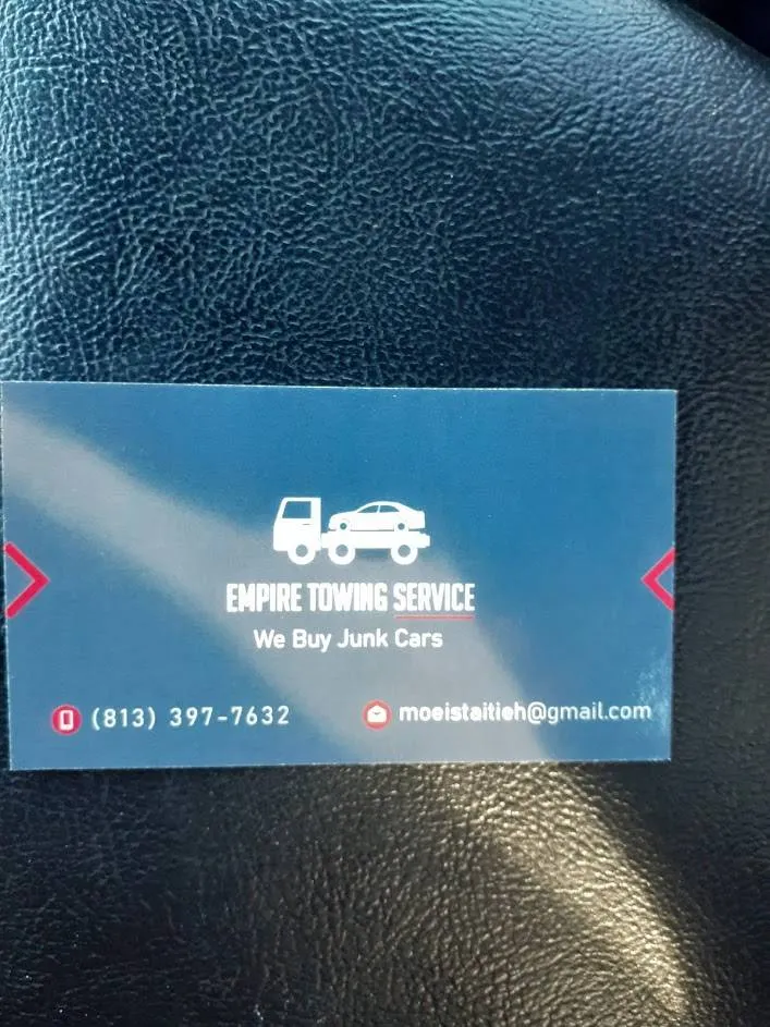 A blue business card for Empire Towing Service lies on black leather